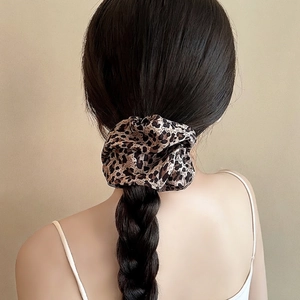 Elegant leopard print scrunchie made of soft fabric shown on a braided hairstyle