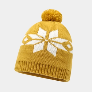 Detailed knit texture of a yellow winter beanie with white snowflake patterns and pompom