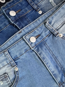 Vista macro de botones metálicos y costuras reforzadas en pantalones cortos de mezclilla