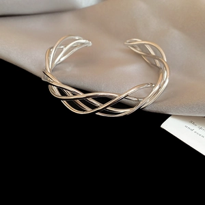 Detail shot of silver irregular layered twisted cuff bracelet on grey silk background