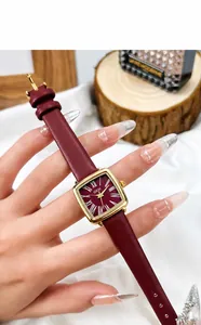 Gros plan d'une montre vintage dorée avec bracelet en cuir rouge bordeaux et chiffres romains