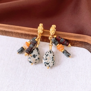 Detail of vintage teardrop earrings with colorful beads and spotted stone on a tray