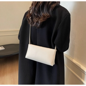 Minimalist beige leather shoulder bag shown on model highlighting elegant side profile
