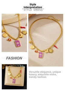 Detail of gold charm necklace featuring evil eye, cherry and sun pendants with gift box