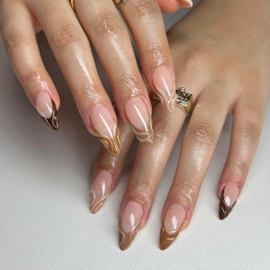 Détail de faux ongles amande avec motifs marbrés marron et style French manucure