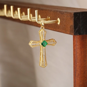 Dettaglio di una collana a croce dorata con pietra verde taglio smeraldo e zirconi