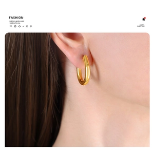 Close-up of chunky gold U-shaped hoop earrings with a high-polished 18K finish