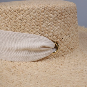 Macro shot of natural raffia straw weaving with herringbone ribbon and golden eyelet
