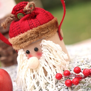 Handcrafted Santa Claus candy jar gift box on snow with festive red berry decorations