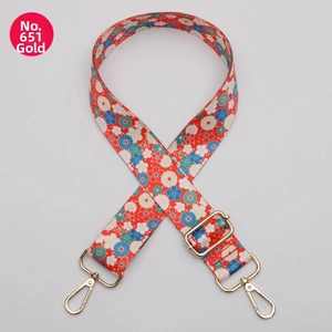 Detail of floral woven bag strap with golden lobster clasps and adjustable buckle