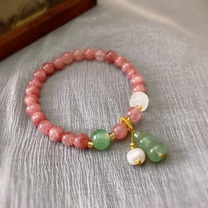 Detailed close-up of pink strawberry quartz bracelet with green jade gourd and pearl