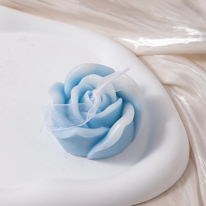 Detailed view of a blue rose scented candle with white ribbon on elegant silk background