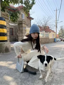 Street style view of cream hooded tracksuit set paired with a silver metallic handbag