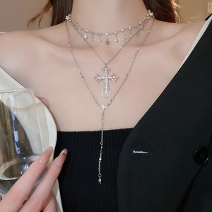 Close-up of layered silver cross and star pendant necklace with sparkling rhinestones