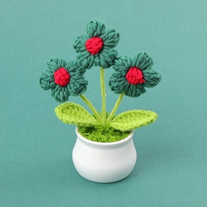 Macro detail of handmade crochet green flower pot with red center in white ceramic base