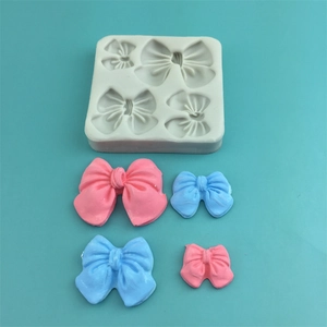 Four-hole bow silicone mold with pink and blue bow crafts on a turquoise surface