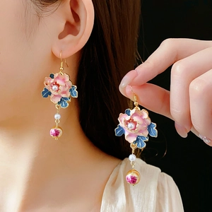 Detail of vintage enamel flower drop earring with pearls and golden tassels on model