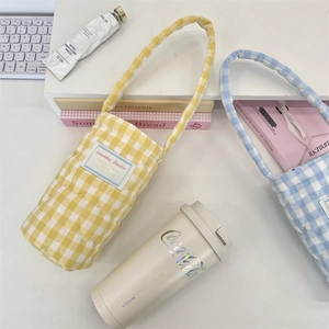 Close-up of diamond quilted plaid cotton cup carrier bag with soft handle and brand label