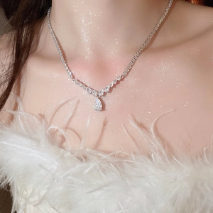 Close-up of sparkling silver teardrop zircon necklace on neck with feather detail