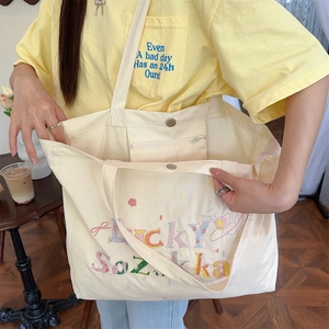 Détail de la broderie Lucky Sazakka sur sac fourre-tout en toile beige à bouton