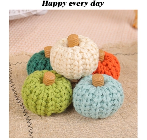 Detail of colorful knitted pumpkins with brown stems on beige linen for fall decor