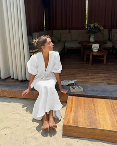 Detail of elegant white V-neck dress featuring puffy sleeves and breathable cotton fabric