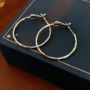 Minimalist large golden hoop earrings with hammer texture displayed on jewelry box