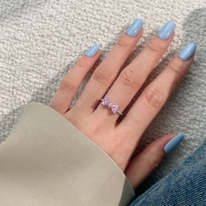 Macro shot of S925 silver bow ring with pink heart zircons worn on hand detail