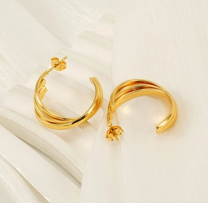 Gros plan sur la texture dorée torsadée des boucles d'oreilles créoles 18K en C