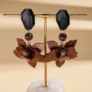 Détail de boucles d'oreilles fleurs en résine vintage sur un support à bijoux doré