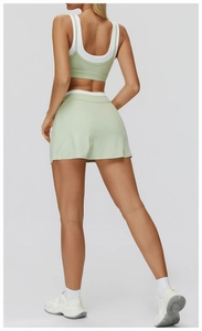 Back view of mint green tennis skirt and sports bra set with white contrast trim details