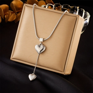 Minimalist silver snake chain necklace with dual heart pendants on gold jewelry box