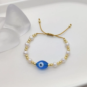 Detail of evil eye pearl bracelet featuring natural pearls and adjustable golden cord