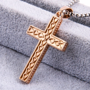 Close-up of rose gold stainless steel cross pendant with intricate textured patterns