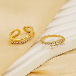 Close-up of golden pearl rings with rhinestones on elegant silk background