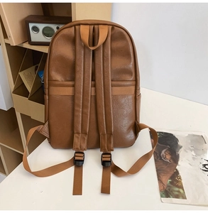 Detailed view of a vintage brown leather backpack on a white desk with retro background