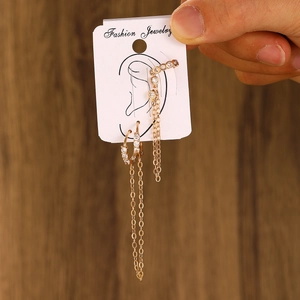 Detail of gold chain tassel earring set with white zircon held against wood