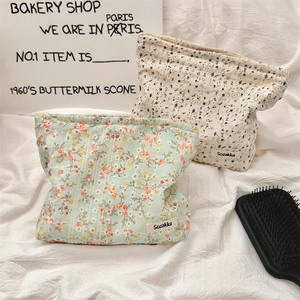 Detail of floral embroidery on canvas cosmetic bags in light green and cream colors