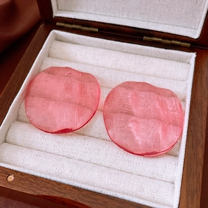 Macro shot of pink resin geometric earrings on wood and velvet jewelry organizer