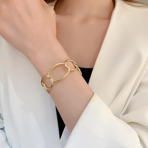 Close-up of golden thick chain bracelet worn over white suit sleeve for elegant style