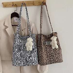 Detail showing animal print canvas tote bags with cute plush bear charms on wooden hooks