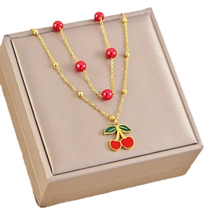 Sweet double-layer gold cherry necklace with red beads on a champagne jewelry box