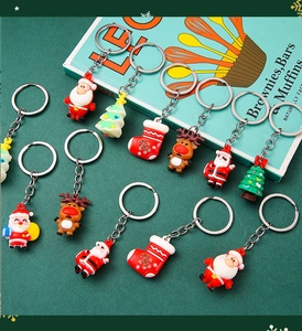 Close-up of festive Christmas keychains featuring Santa and tree on dark background