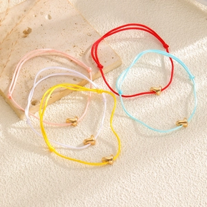Détail de bracelets en corde colorée avec pendentifs cœur dorés polis sur pierre