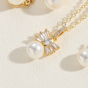 Macro detail of gold bow necklace featuring white pearl and sparkling zircon stones