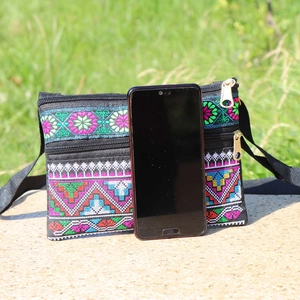 Detailed embroidery on ethnic crossbody bag showing texture and size with a smartphone