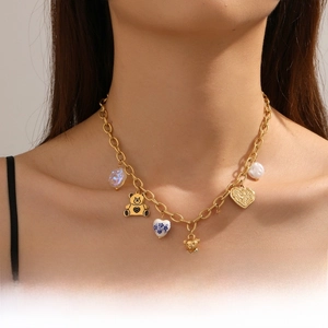 Detail of gold plated chain necklace with 3D bear and colorful heart pendants on neck
