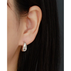Macro shot of S925 sterling silver C-shaped earring with sparkling crystal waterdrop charm