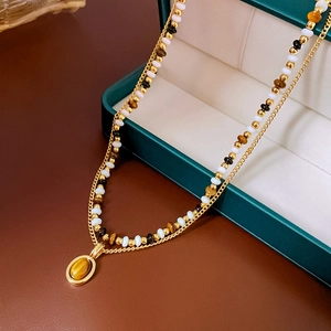 Detail of a double-layer gold necklace with tiger eye pendant in a green jewelry box