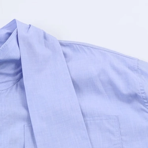 Dettaglio camicia azzurra con tessuto a trama fitta e cuciture precise sulle spalle
